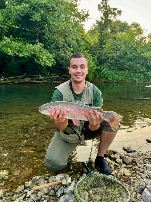 Trout held above the water by a guide